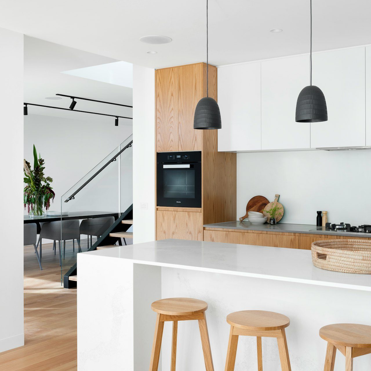 Cuisine moderne avec comptoir en marbre, tabourets en bois et décoration épurée.