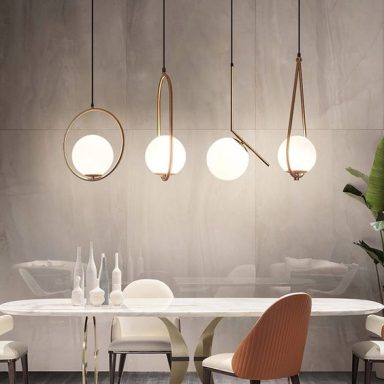Quatre suspensions modernes avec des globes lumineux au-dessus d'une table élégante.