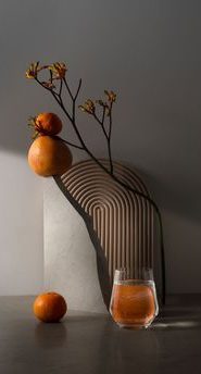Verre de jus d'orange avec des oranges et une branche sur une table.