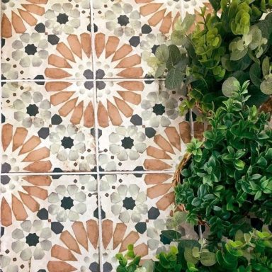 Carrelage coloré aux motifs floraux, entouré de verdure.