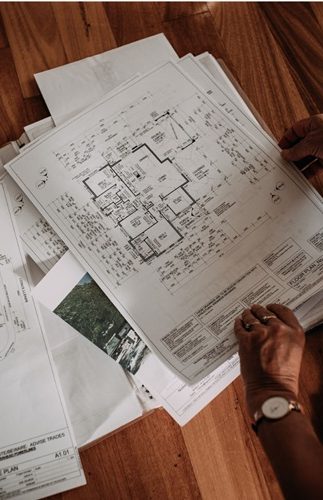 Plans architecturaux et documents techniques étalés sur une surface en bois.