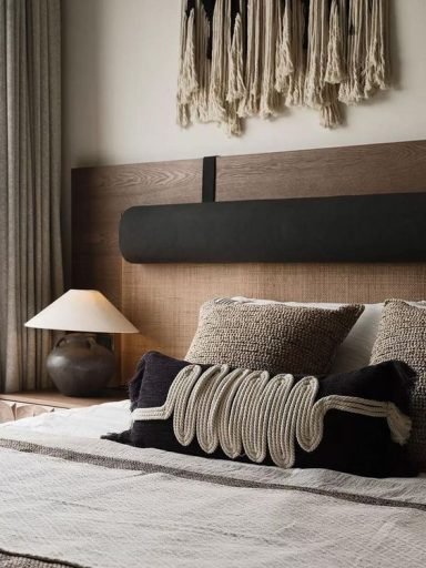 Lit de chambre avec coussins décoratifs et lampe vintage, ambiance minimaliste.