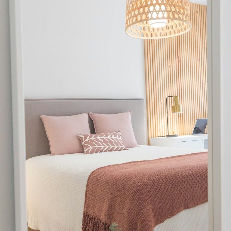 aménagement chambre/cuisine/salon/entrée Chambre moderne avec lit double, coussins roses et lampe au design épuré.