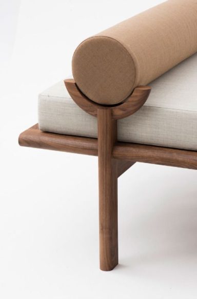 Détail d'un canapé moderne avec un coussin rond et une base en bois.