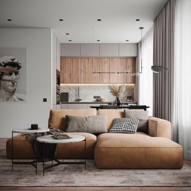 Salon moderne avec un canapé en tissu, tables basses et cuisine ouverte en arrière-plan.