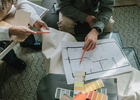 Deux personnes examinent des plans avec des échantillons de couleurs sur une table.
