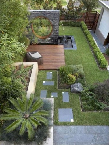 Jardin moderne avec pelouse, dalles, mûrs en pierre et un coin détente en bois.