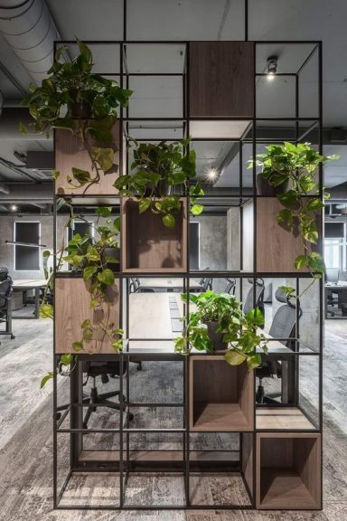 Bibliothèque séparation de bureau moderne avec des plantes verdoyantes et des espaces de rangement en bois.