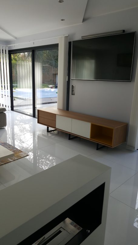 Intérieur moderne avec un meuble TV en bois et un grand écran, lumières naturelles.