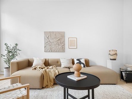 Salon moderne avec canapé beige, table noire et décor minimaliste.