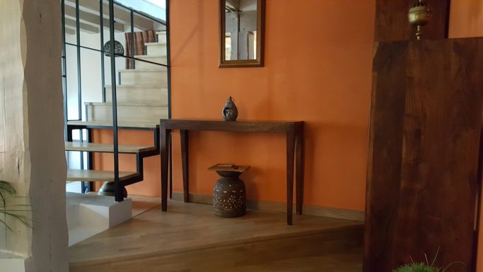 Intérieur moderne avec un mur orange, une console en bois et une plante verte.