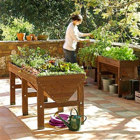 Personne jardinant dans un potager en bois, entouré de plantes et de pots.