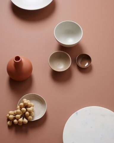 Assortiment de bols et d'une carafe sur une surface beige, avec des éléments en bois.