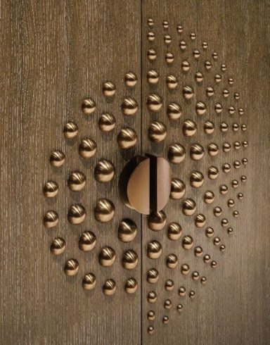 Porte en bois avec un motif de boules dorées et une poignée centrale.