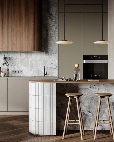 Cuisine moderne avec îlot en bois, chaises en bois et éclairage suspendu.