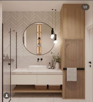 Salle de bain moderne avec un meuble en bois, miroir rond et éclairage suspendu.